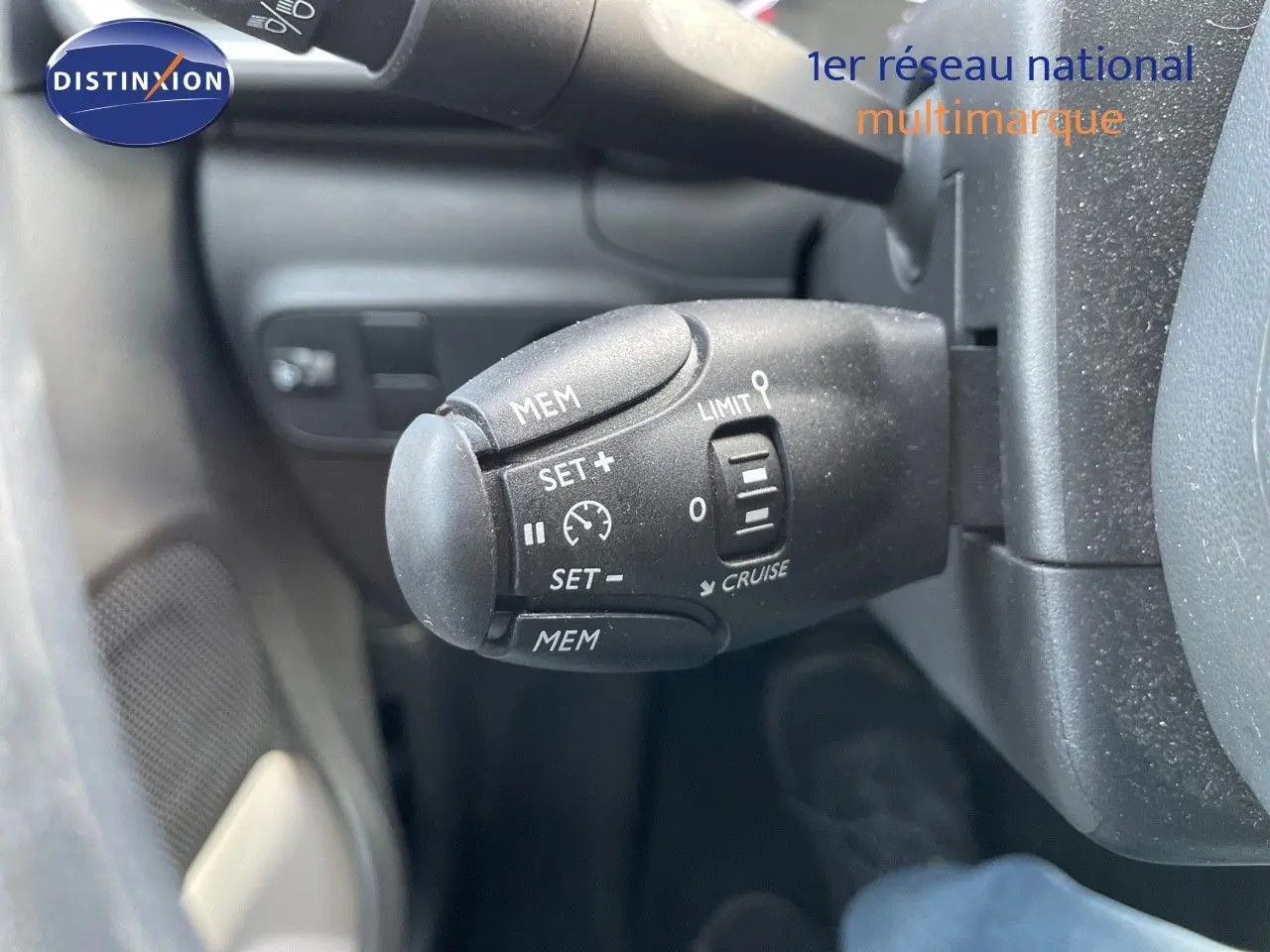 Gros plan sur la commande de régulateur de vitesse à gauche du volant dans l'habitacle d'une Citroën C3 gris platinium.