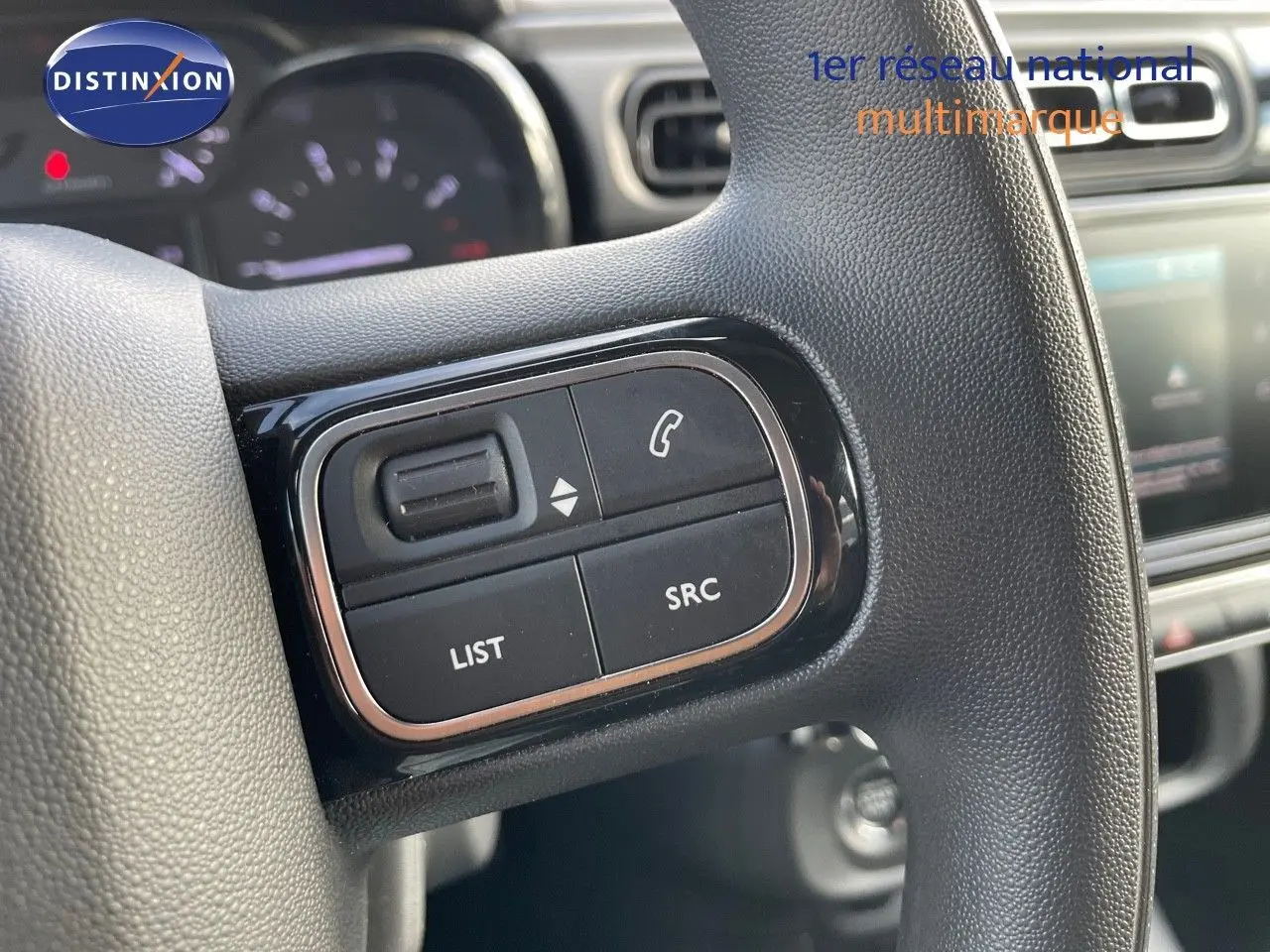 Gros plan sur les commandes multimédia noires à gauche du volant de la Citroën C3 gris platinium 2023.