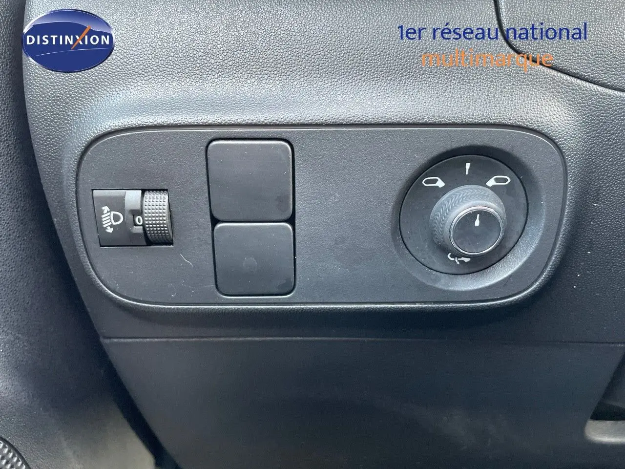 Gros plan sur les commandes de réglage des rétroviseurs et des phares d'une Citroën C3 gris platinium 2023.