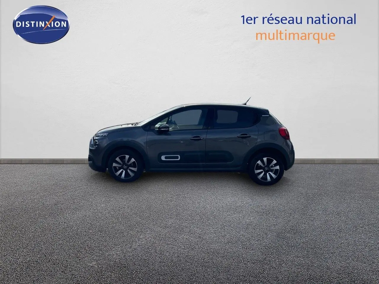 Profil côté gauche d'une Citroën C3 2023 gris platinium métallisé avec jantes bi-ton et protections latérales blanches.