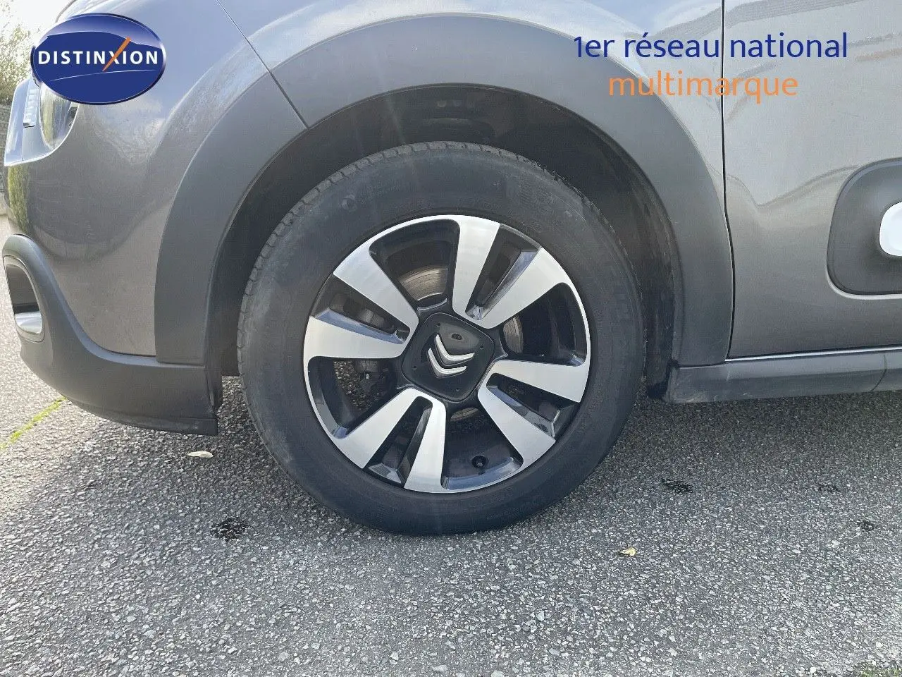 Gros plan sur la roue avant gauche d'une Citroën C3 gris platinium métal, mettant en valeur la jante bi-ton moderne.