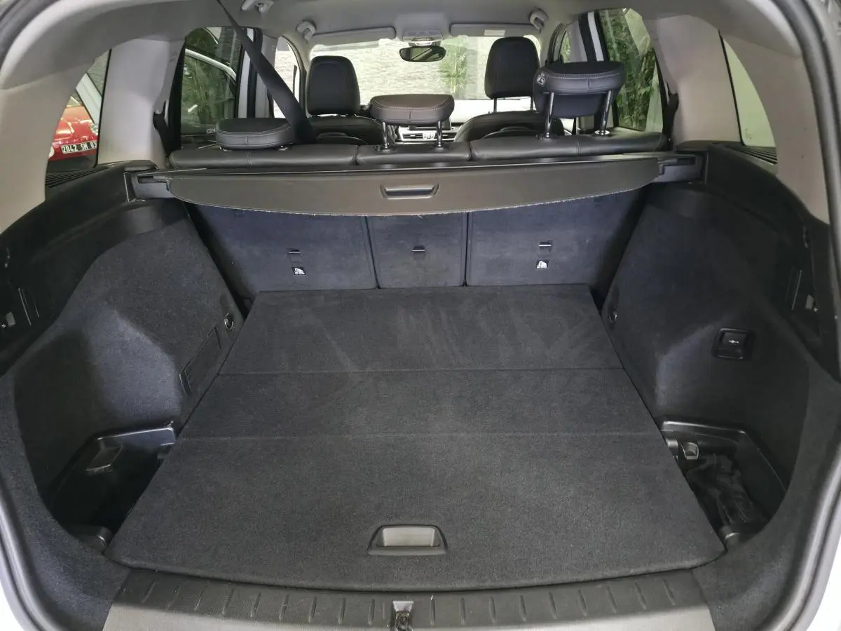 Coffre spacieux de BMW Série 2 Gran Tourer blanc, vue arrière avec banquette rabattue et cache-bagages noir.