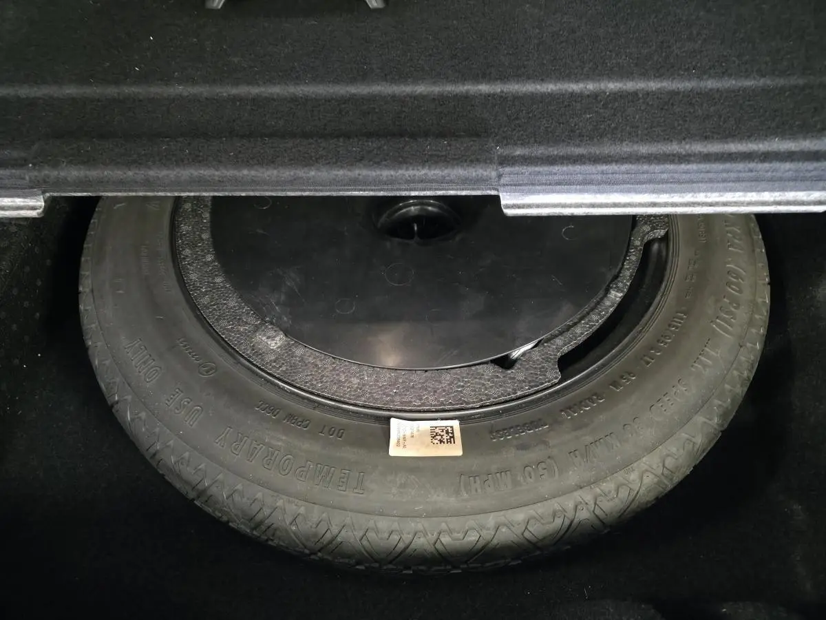 Gros plan sur la roue de secours dans le coffre d'une BMW Série 2 Gran Tourer blanche.