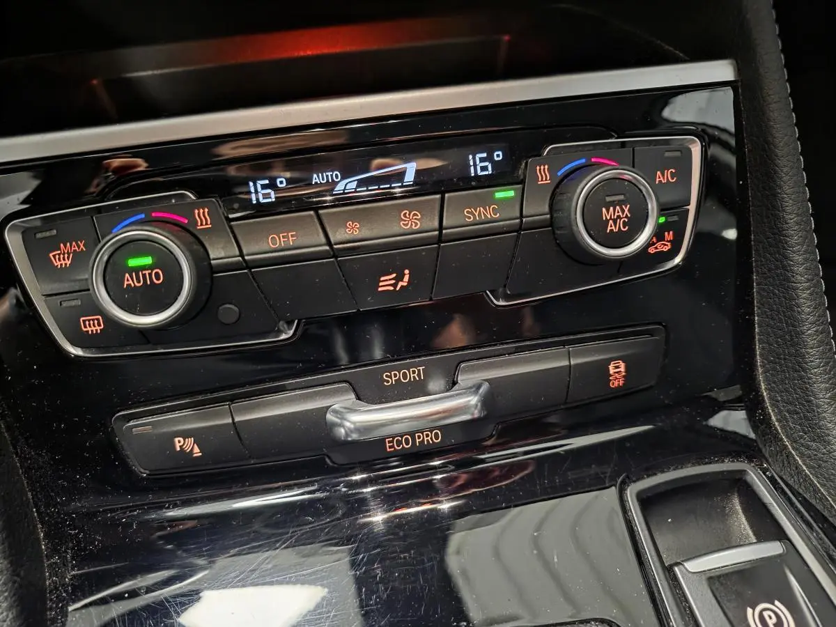 Gros plan sur la console centrale noire brillante avec commandes climatisation et modes de conduite BMW Série 2 Gran Tourer.