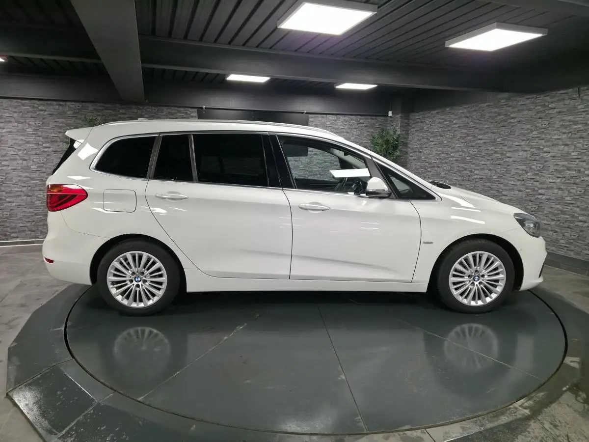 BMW Série 2 Gran Tourer blanc vue de profil côté gauche avec jantes alliage 17 pouces en intérieur showroom.