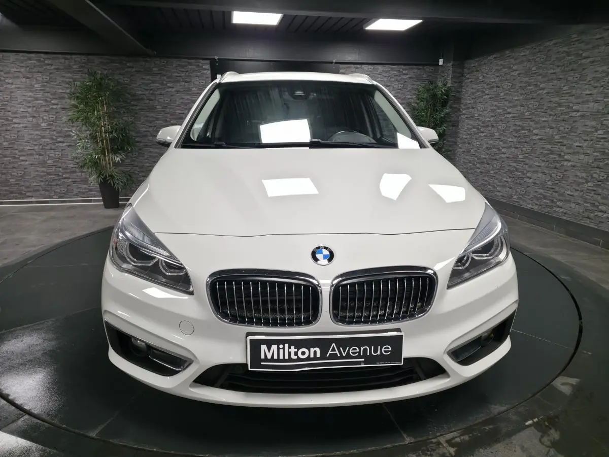 Vue frontale d'une BMW Série 2 Gran Tourer blanche avec calandre chromée et phares LED dans un showroom.