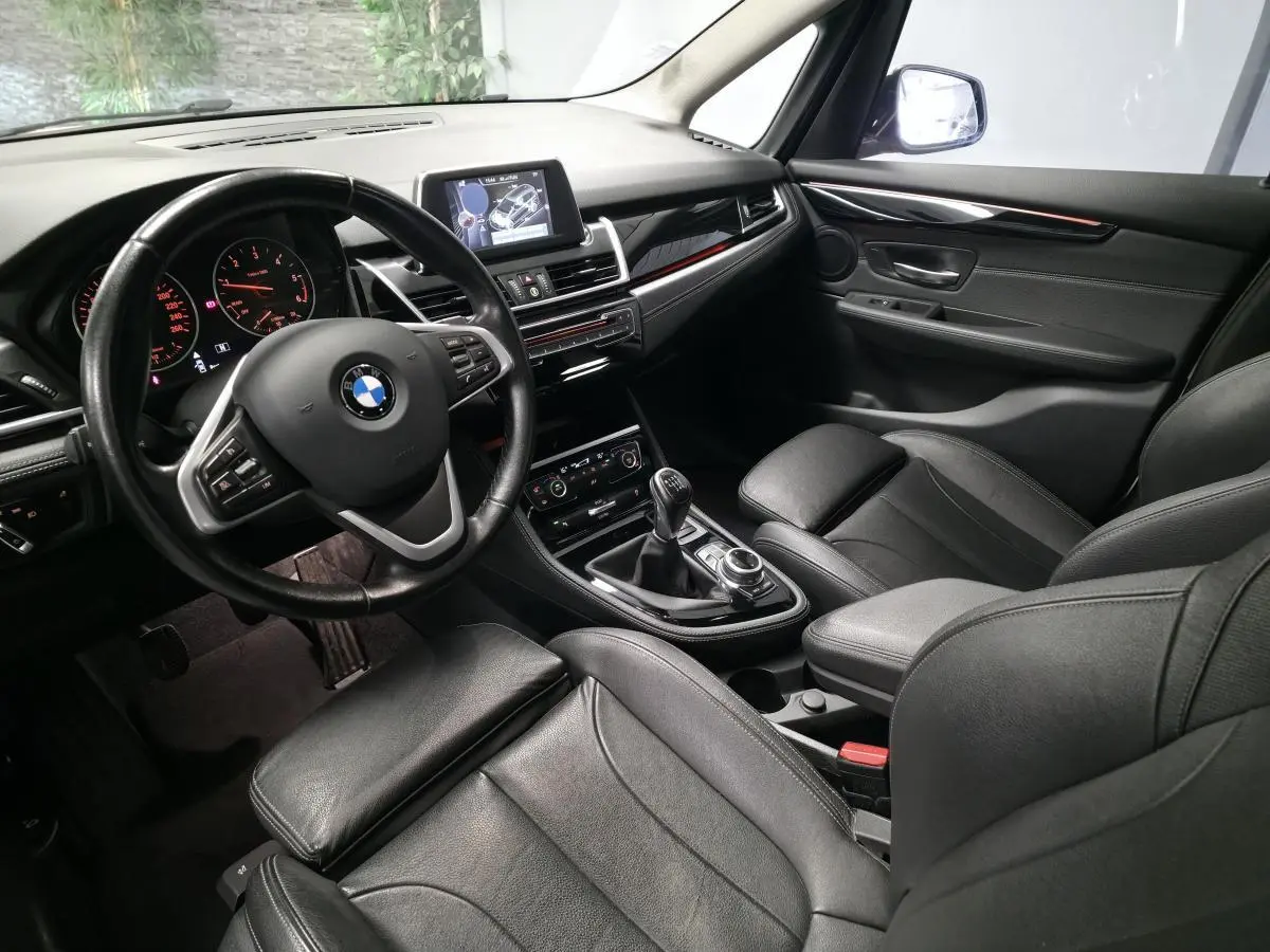 Intérieur BMW Série 2 Gran Tourer vu côté conducteur, sellerie cuir noire et console centrale avec boîte manuelle.