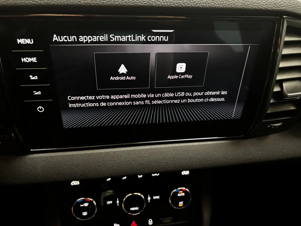 Écran tactile central affichant la connexion Android Auto et Apple CarPlay dans le tableau de bord noir du Skoda Karoq 2025.