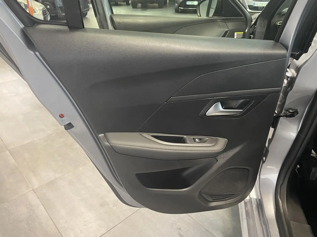 Porte arrière droite ouverte d'une Peugeot 208 2025 gris Artense avec garniture noire et accoudoir gris clair surpiqué