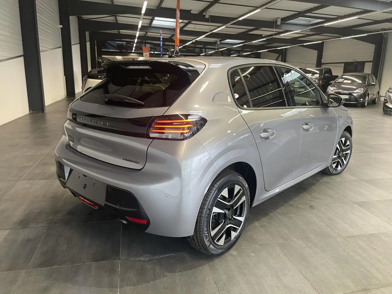 Peugeot 208 hybride gris Artense vue 3/4 arrière droit avec feux arrière LED et jantes alliage bi-ton.