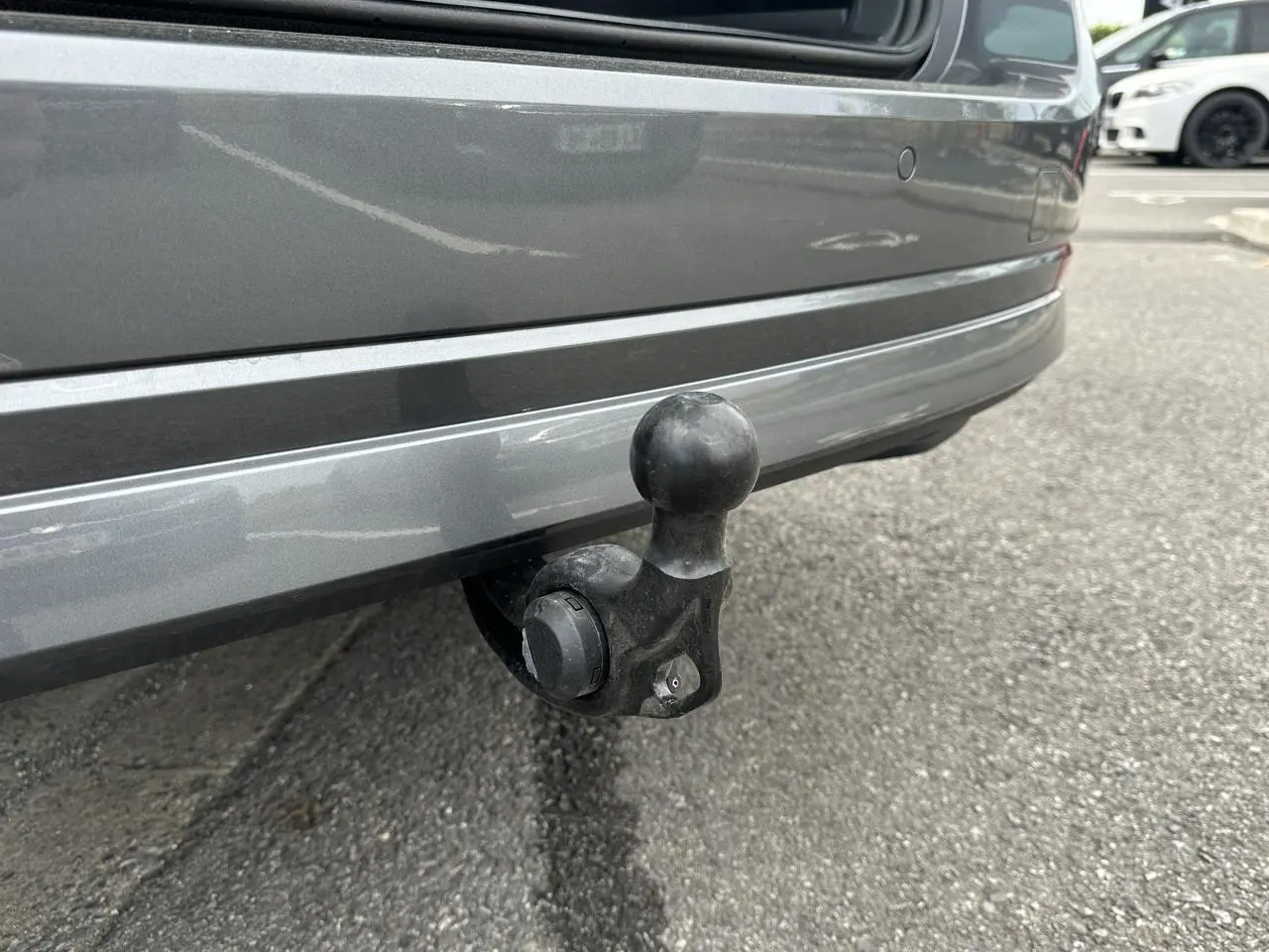 Gros plan sur le crochet d'attelage pivotant noir sous le pare-chocs arrière gris graphite d'une Skoda Octavia Combi 2024.