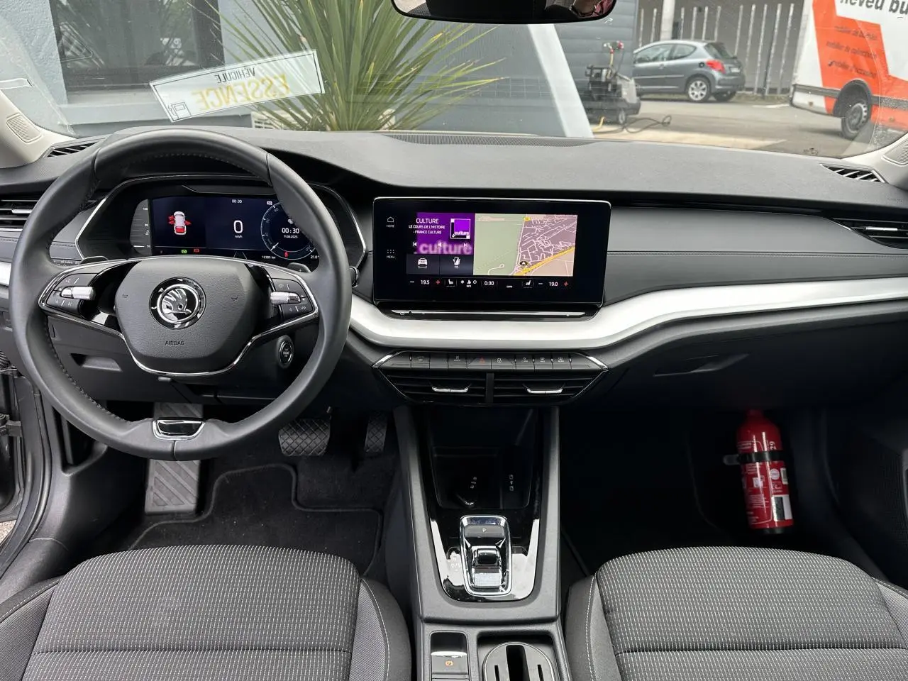 Intérieur de la Skoda Octavia Combi 2024 vu de face, tableau de bord noir avec écran tactile et volant multifonctions.