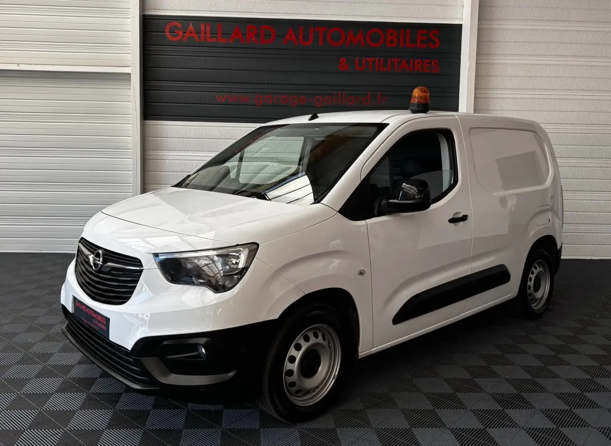 Opel Combo blanc en 3/4 avant droit avec gyrophare orange sur le toit et jantes acier simples.