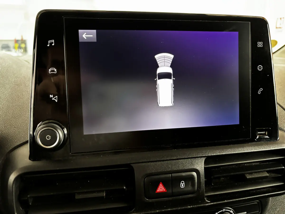 Écran tactile intérieur de l’Opel Combo 2021 affichant l’aide au stationnement avec vue du véhicule blanc en haut.