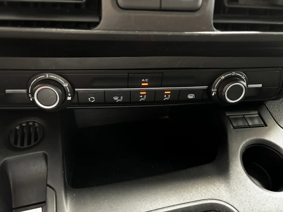 Gros plan sur la console centrale noire de l'Opel Combo 2021 montrant les commandes de climatisation avec voyants allumés.