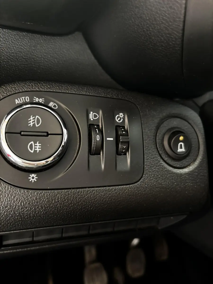 Gros plan sur les commandes d'éclairage et réglages du tableau de bord noir de l'Opel Combo blanc 2021.