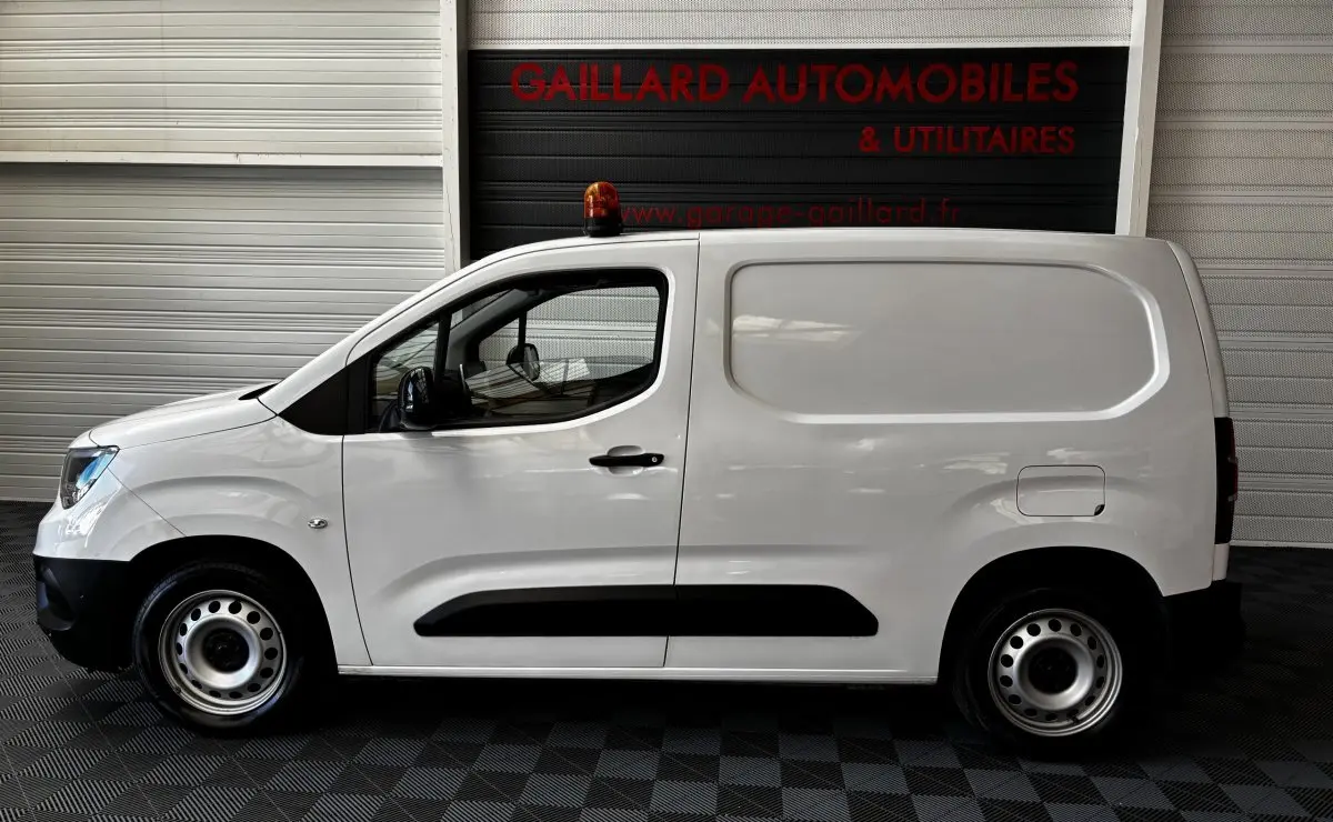 Profil côté gauche d'un utilitaire blanc Opel Combo 1.5 diesel 100ch avec gyrophare orange sur le toit.