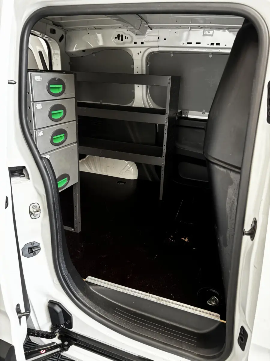 Vue intérieure de la zone de chargement du fourgon blanc Opel Combo 2021 avec étagères métalliques et cloison pleine noire.