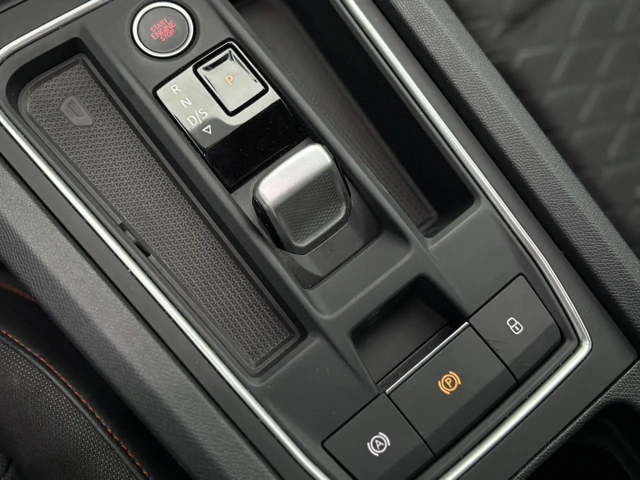 Vue rapprochée de la console centrale noire avec levier de boîte auto et bouton Start du SEAT LEON 1.5 e-TSI 2024.
