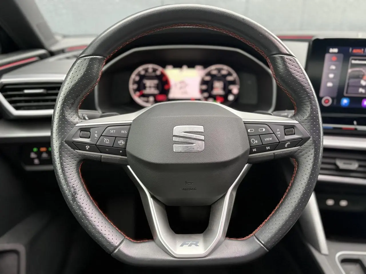 Volant cuir perforé avec surpiqûres rouges et logo FR du SEAT LEON 1.5 e-TSI 150 DSG7 vue de face intérieure