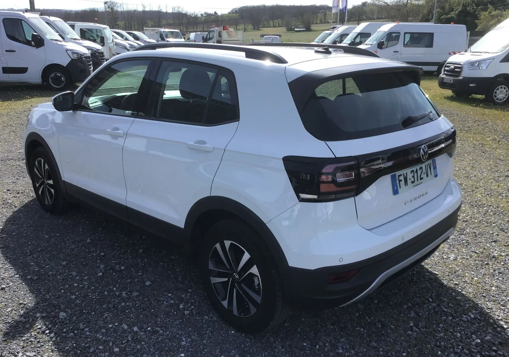 Volkswagen T-Cross blanc vue 3/4 arrière droit, avec jantes alliage noires et vitres arrière teintées.