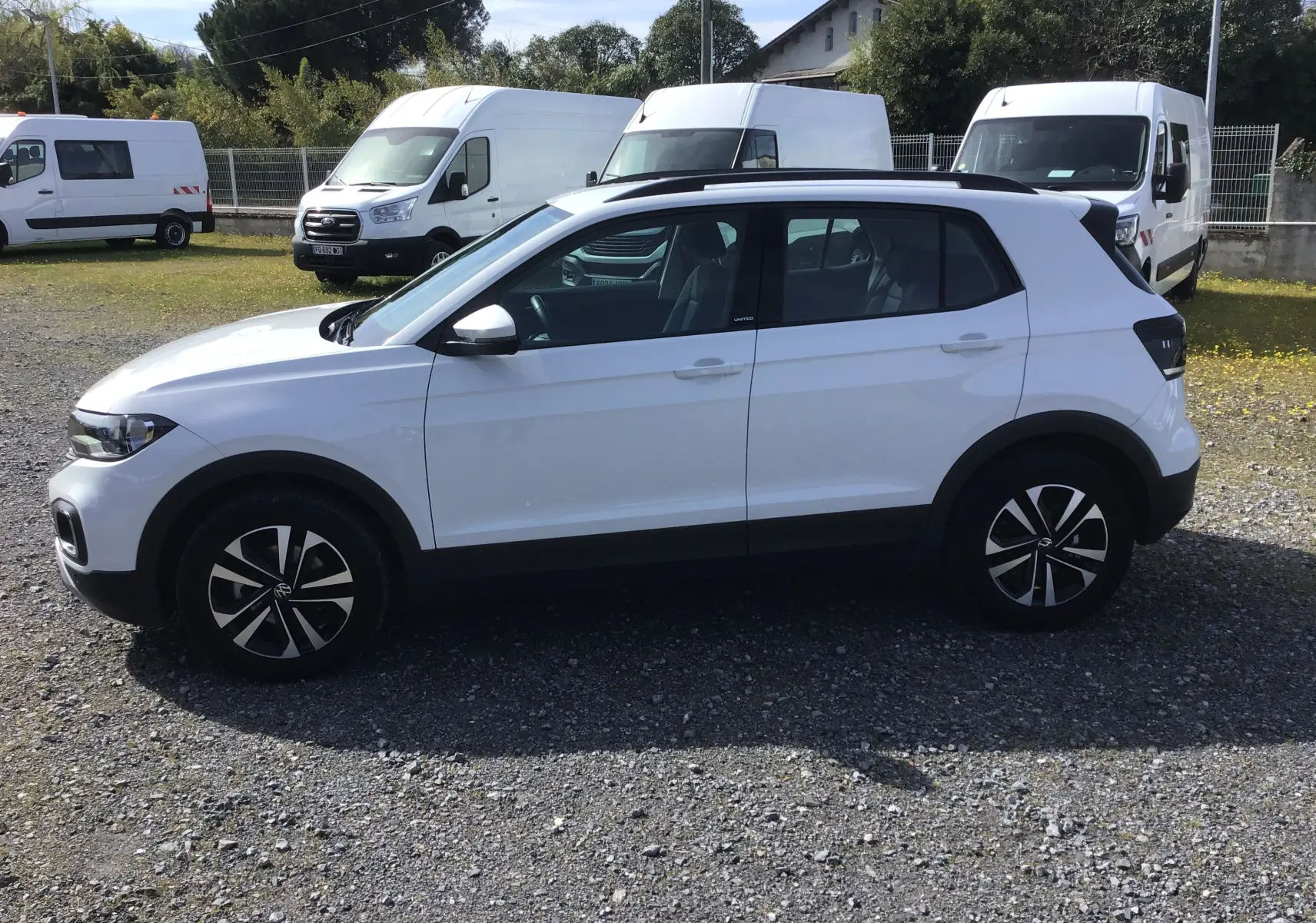 Vue de profil côté gauche d’un Volkswagen T-Cross blanc 2021 avec jantes alliage noires et toit noir contrasté.
