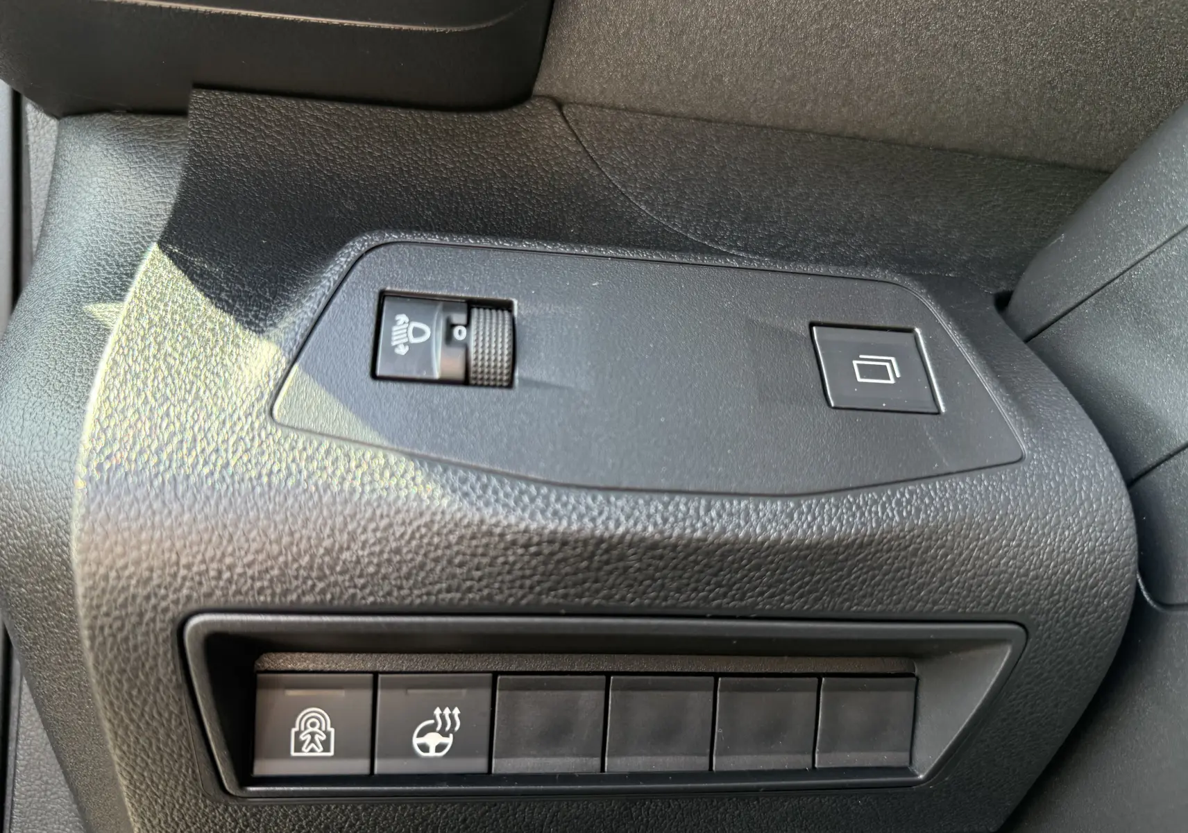 Gros plan sur le volant cuir gris clair du Peugeot Rifter 2026 avec commandes multifonctions et logo Peugeot noir brillant.