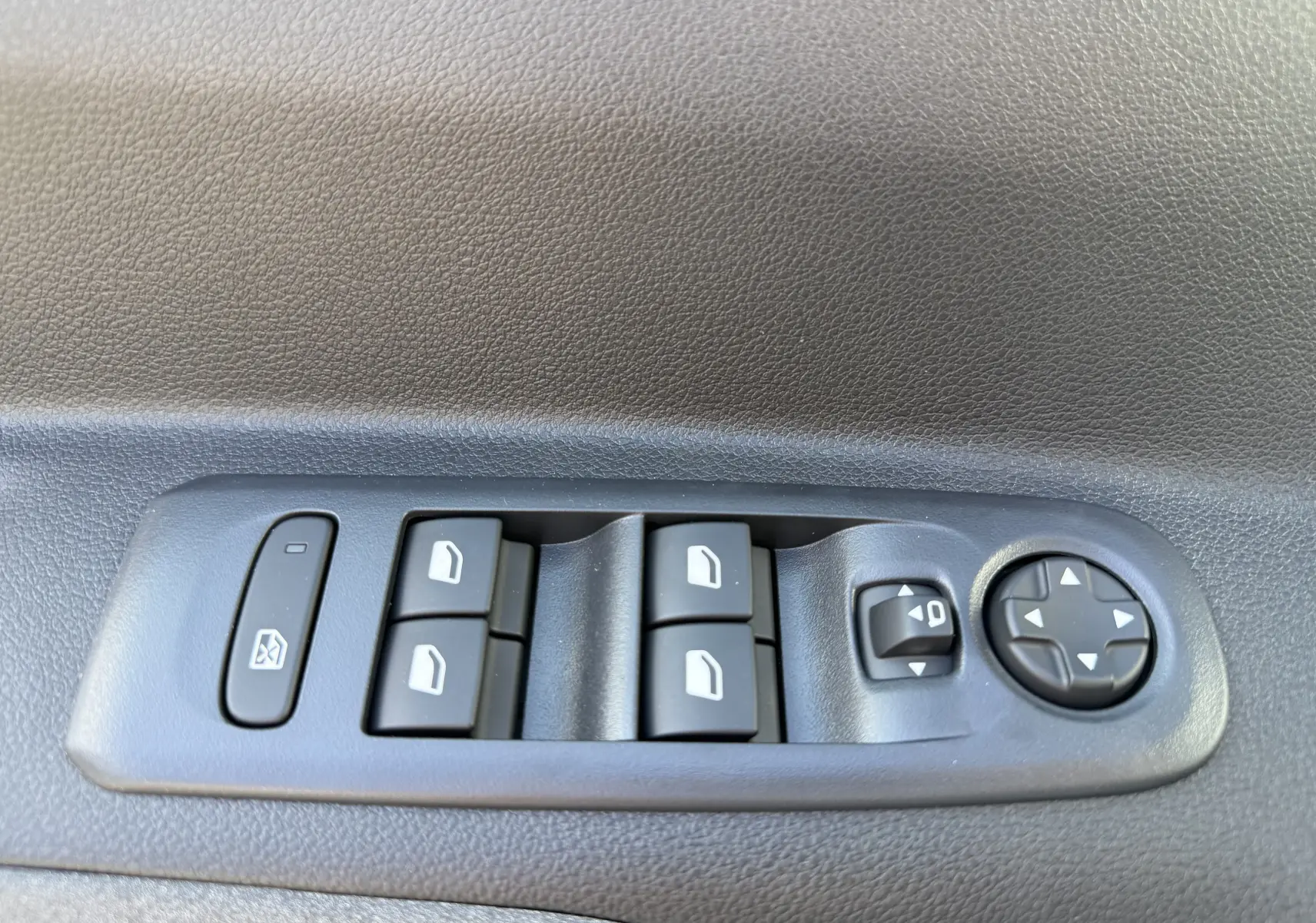 Gros plan sur le volant cuir gris du Peugeot Rifter Allure 2026, avec commandes audio et logo lion au centre.