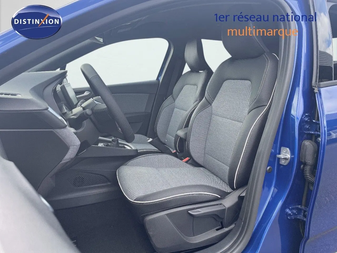 Vue intérieure côté conducteur d'une Renault Clio 2025 bleu Iron Metal avec sièges tissu gris et cuir noir.