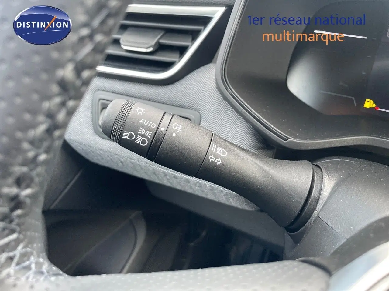 Gros plan sur la commande des phares à gauche du volant d'une Renault Clio bleu Iron Metal 2025, intérieur moderne.