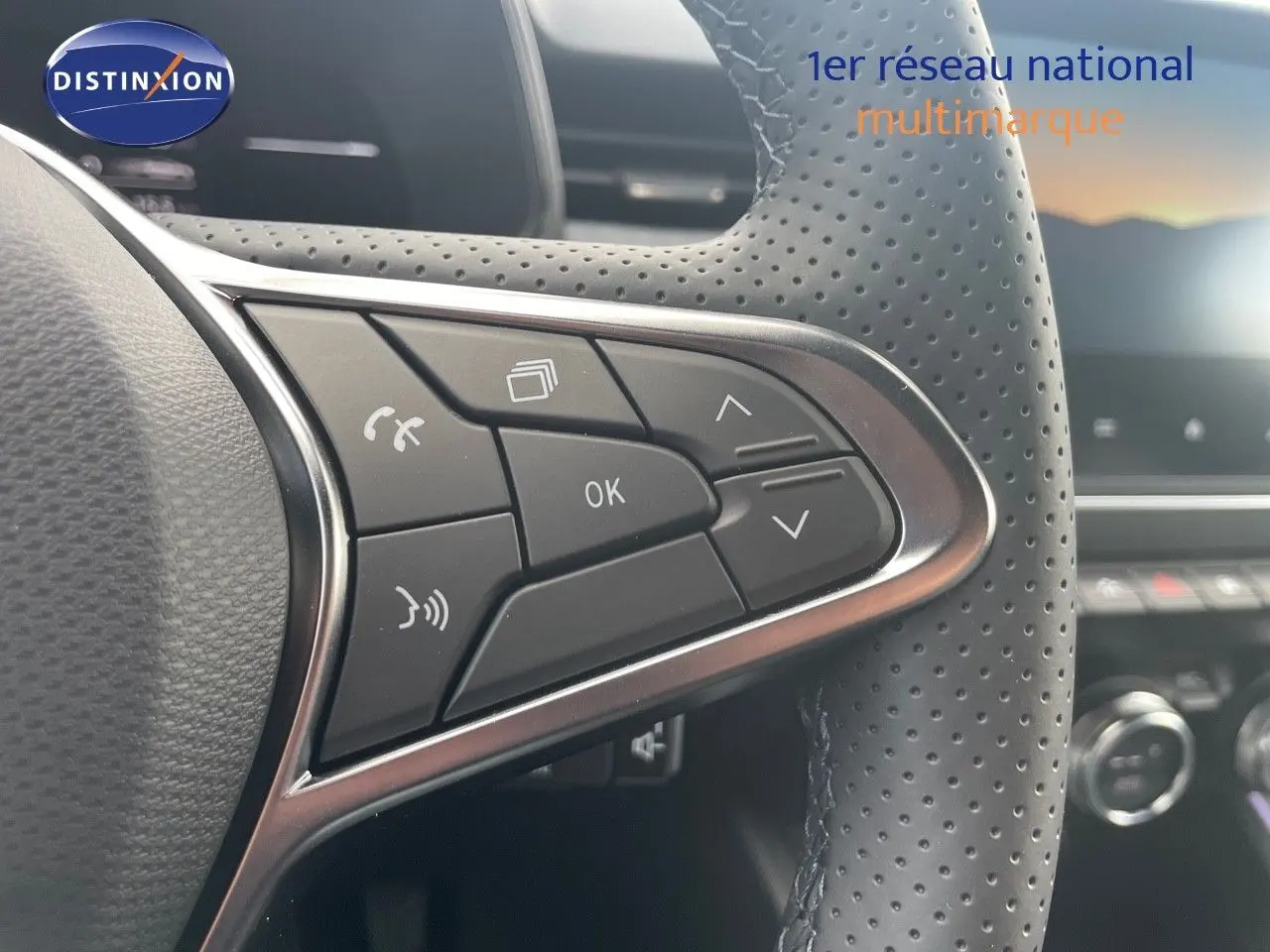 Gros plan sur les commandes du volant en cuir perforé de la Renault Clio TCE 90CH TECHNO bleu Iron Metal, intérieur moderne.