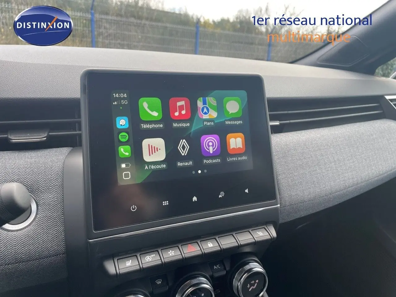 Écran tactile central allumé avec interface Renault, tableau de bord gris texturé, vue de l'habitacle avant droit.