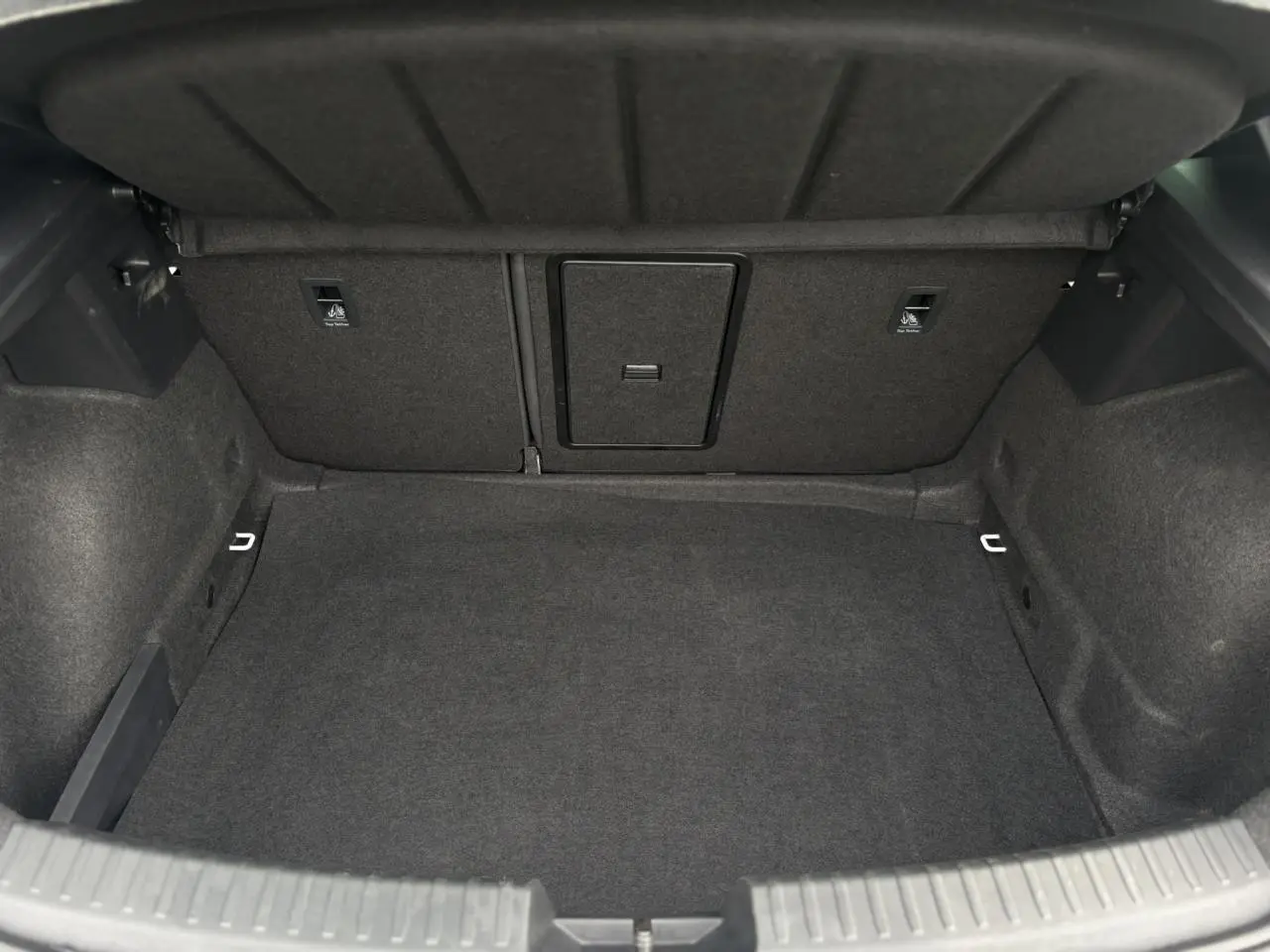 Coffre spacieux et vide de la SEAT LEON 1.5 e-TSI 150 DSG7 FR, vue intérieure arrière avec revêtement gris foncé.