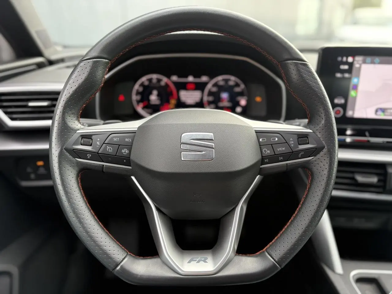 Vue rapprochée du volant cuir perforé noir avec logo FR de la SEAT LEON 1.5 e-TSI 150 DSG7 2024.