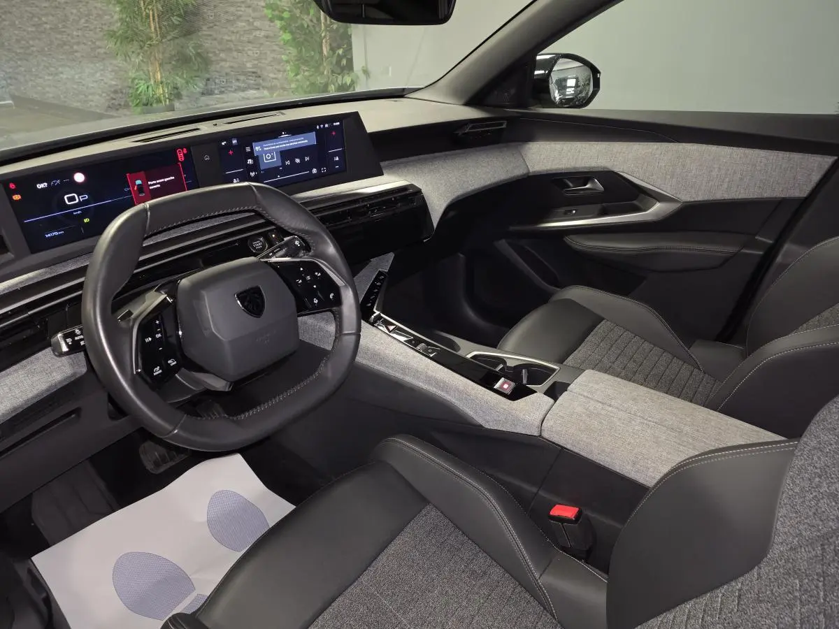 Intérieur avant droit du Peugeot 3008 gris 2025, avec tableau de bord numérique et sellerie tissu gris et cuir noir.