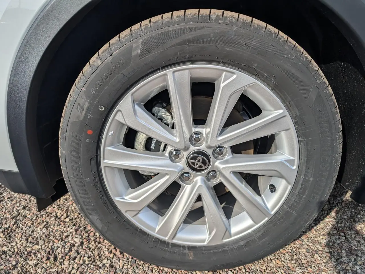 Gros plan sur la jante alliage 17 pouces argentée du Toyota C-HR blanc, avec logo Toyota au centre.