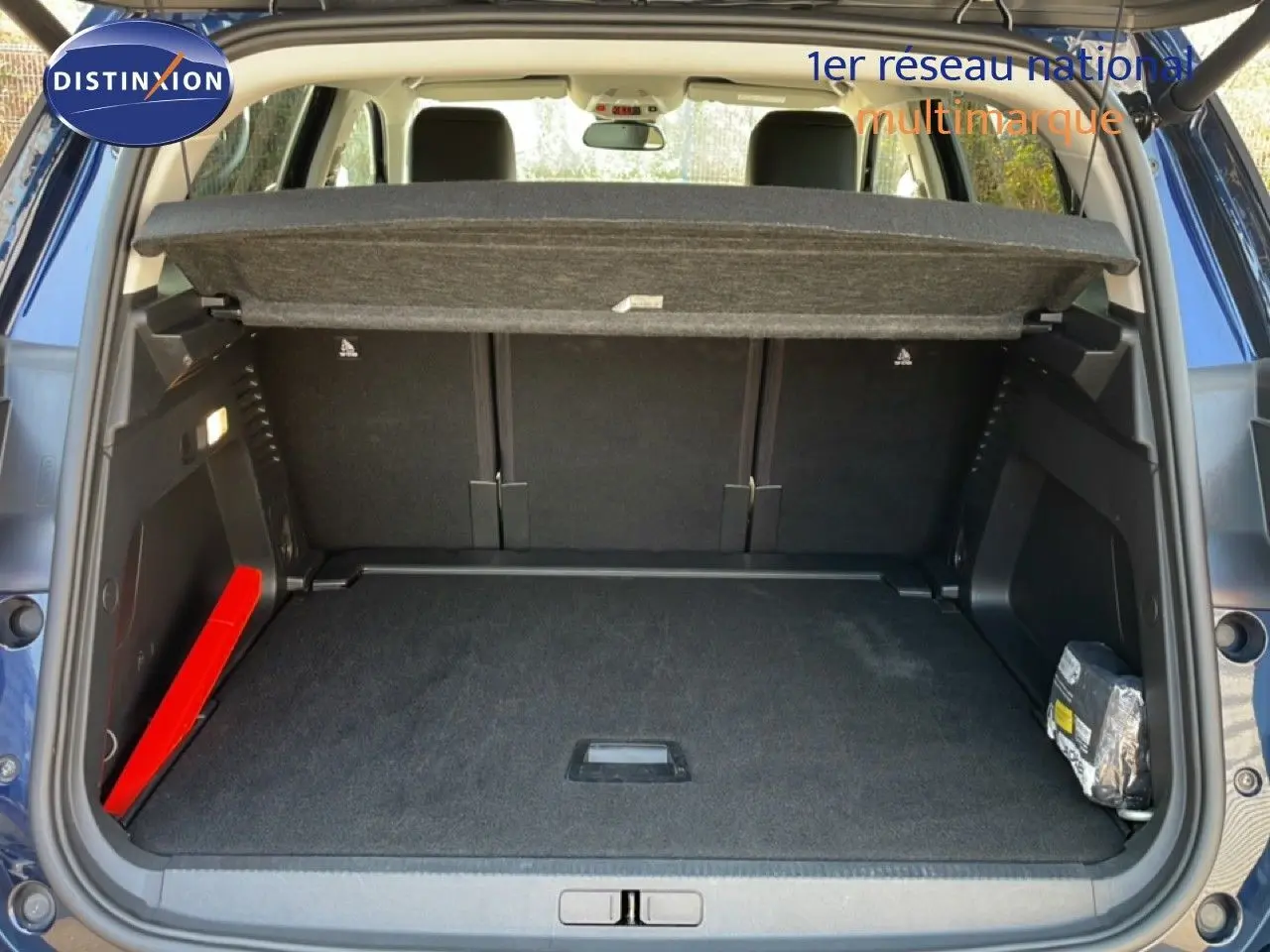 Coffre ouvert vu de l'arrière d'un Citroën C5 Aircross bleu Eclipse Métal, avec cache-bagages et intérieur noir.