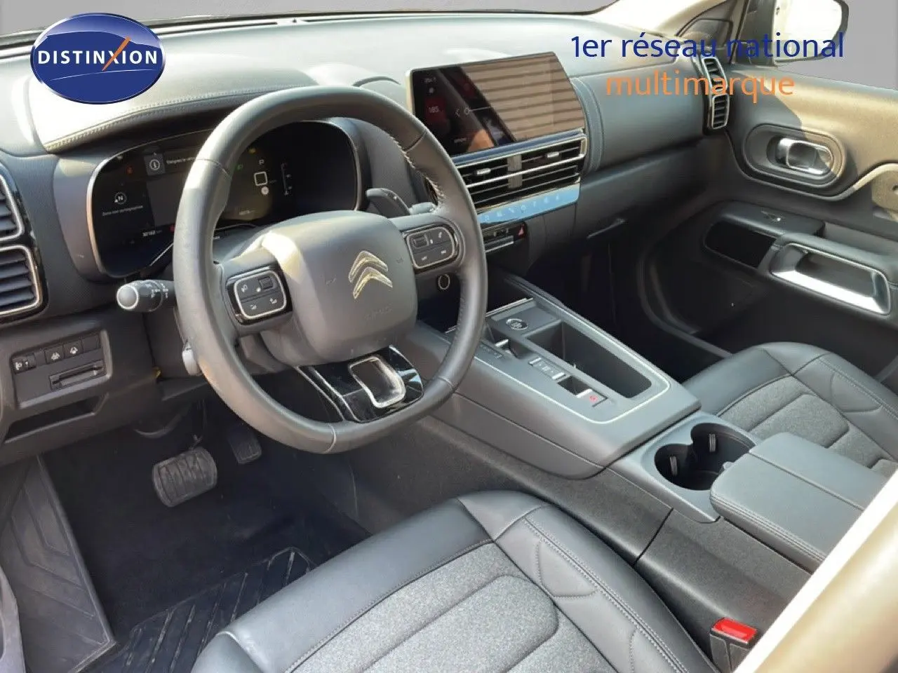 Intérieur avant du Citroën C5 Aircross 2025, vue côté conducteur, tableau de bord moderne et sièges gris noir en tissu et cuir.
