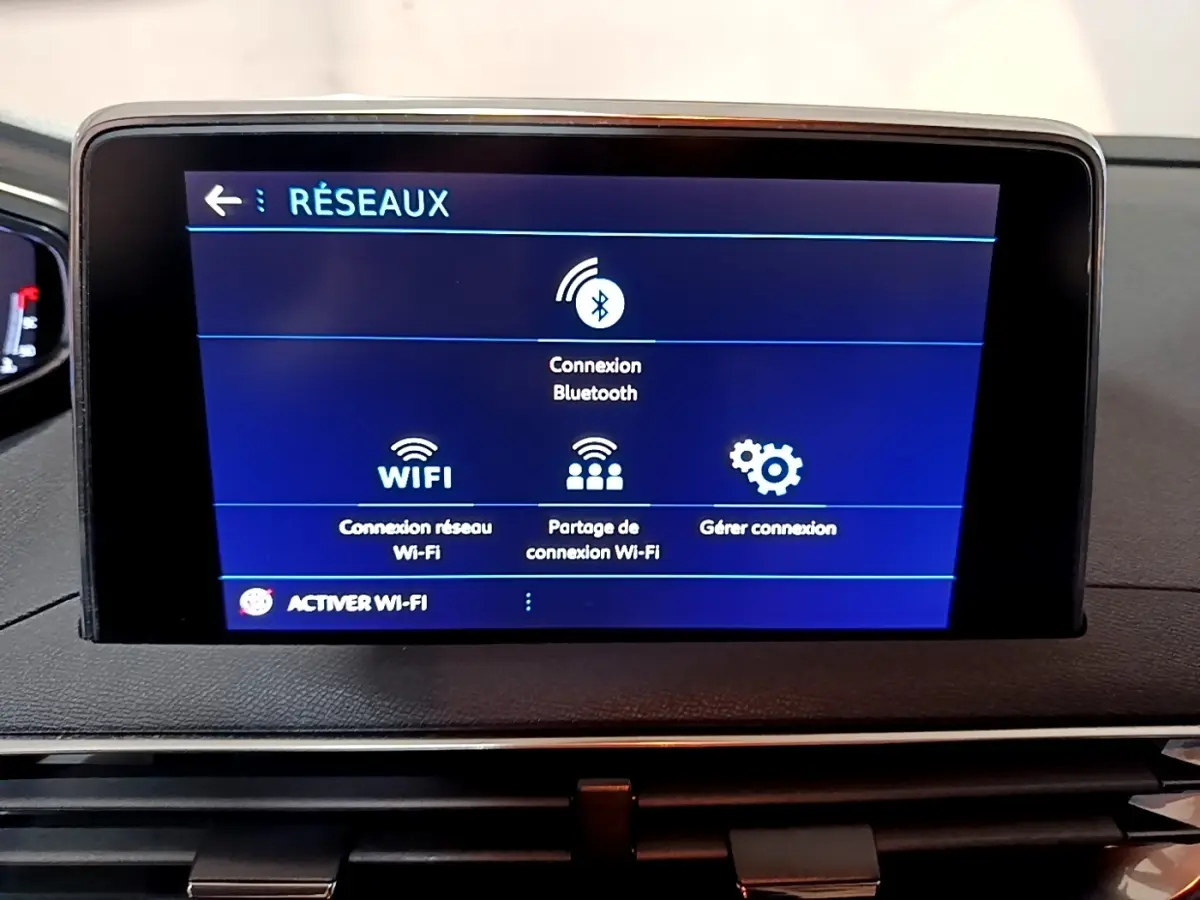 Écran tactile central affichant les options réseau Bluetooth et Wi-Fi dans un Peugeot 5008 gris clair, vue intérieure frontale.