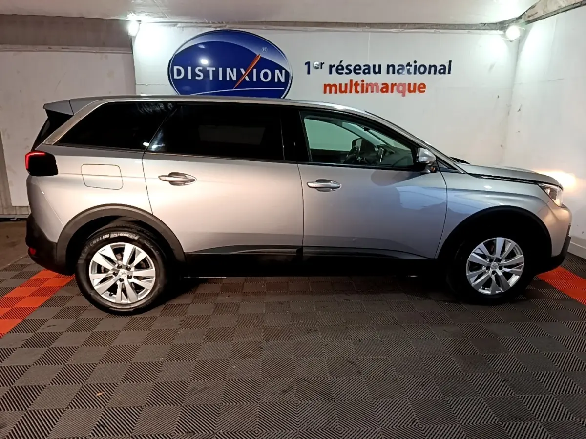 Vue latérale droite d'un Peugeot 5008 gris clair 2020 stationné en intérieur, avec jantes alliage et vitres teintées.