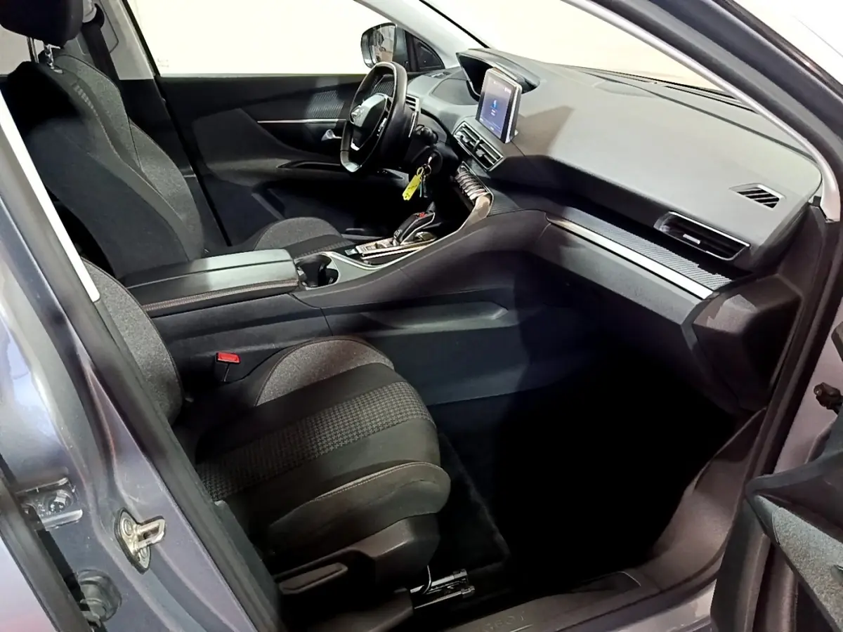 Vue intérieure côté conducteur du Peugeot 5008 gris clair 2020, mettant en valeur le tableau de bord et l'écran tactile central.