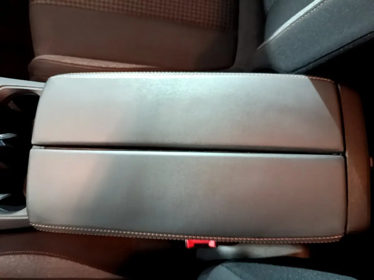 Vue plongeante sur l'accoudoir central en cuir gris clair du Peugeot 5008, avec surpiqûres blanches visibles.