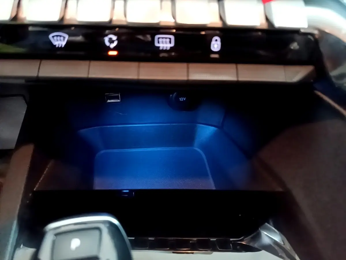 Gros plan intérieur sur la console centrale du Peugeot 5008 gris clair, avec levier de boîte automatique et prises USB et 12V.