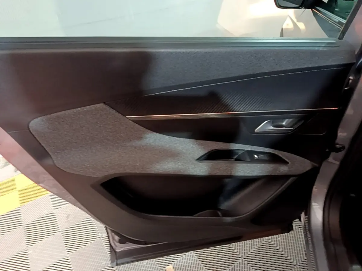 Porte arrière droite ouverte de Peugeot 5008 gris clair, avec habillage tissu et plastique noir, poignée argentée visible.