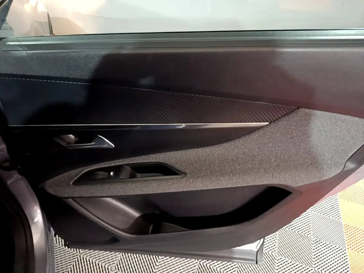 Détail de la porte intérieure côté conducteur du Peugeot 5008 gris clair, avec habillage tissu et plastique noir.