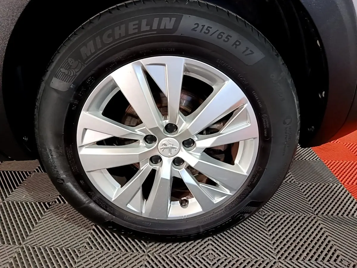 Gros plan sur la roue avant droite d’un Peugeot 5008 gris clair avec jante alliage et pneu Michelin.