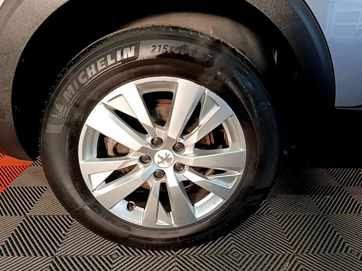 Gros plan sur la roue avant droite du Peugeot 5008 gris clair, avec jante alliage et pneu Michelin visible.