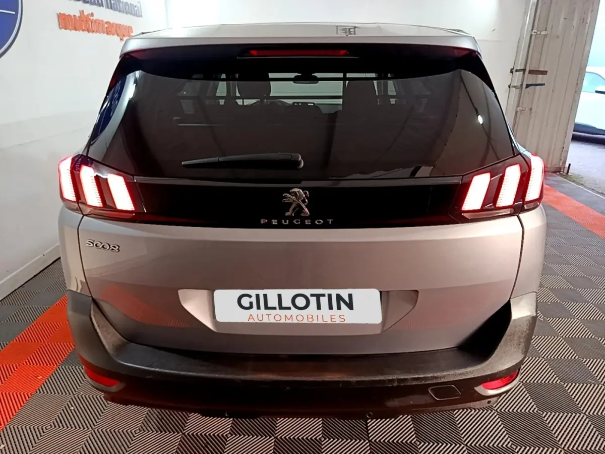 Vue arrière d’un Peugeot 5008 gris clair avec feux LED allumés et logo Peugeot bien visible sur le hayon.