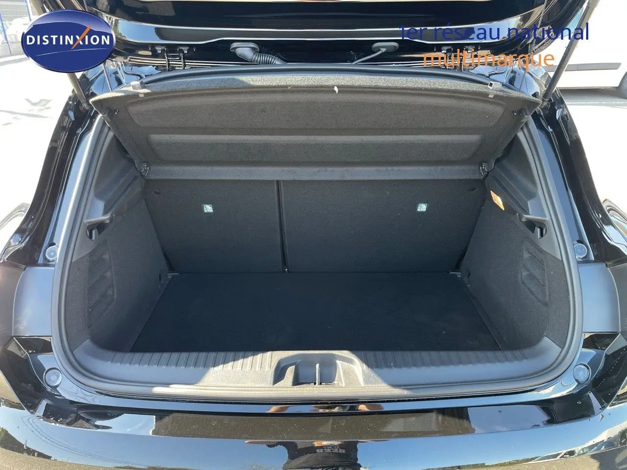 Coffre ouvert d'une Renault Clio TCE 90CH TECHNO noir métal, vue arrière montrant l'espace de chargement vide.