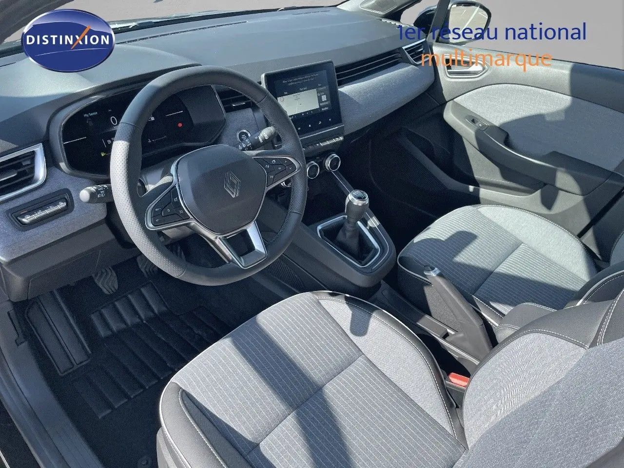 Intérieur de Renault Clio TCE 90CH TECHNO 2025, vue côté conducteur, sièges gris clair et volant multifonction noir.